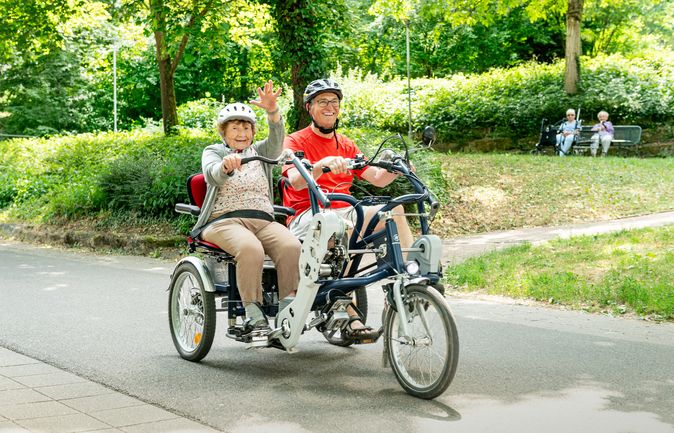 Älteres Paar mit Helmen auf Paralleltandem im Park