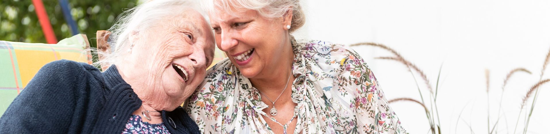 Ältere Frau und jüngere Frau lachen und halten Garn und bunte Decke