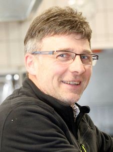 Lächelnder Mann mit Brille und dunkler Jacke in Küche