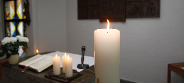 Brennende Kerzen und aufgeschlagenes Buch auf Altar